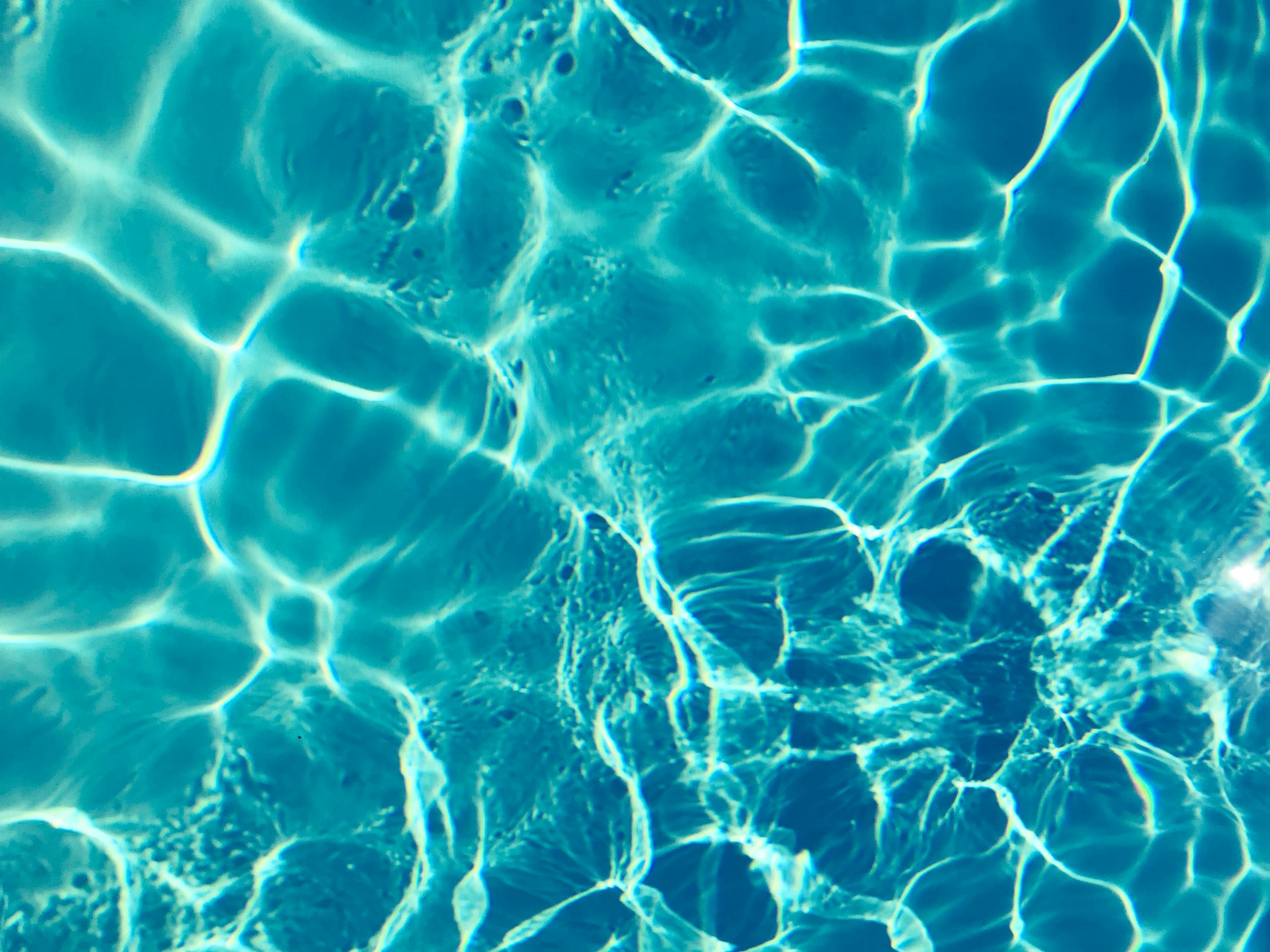 Bright turquoise water surface in sunlight, capturing shimmering patterns and reflections.